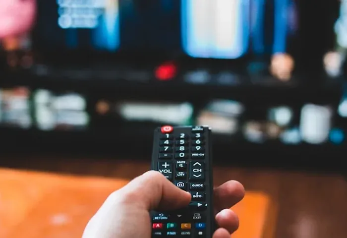 Hand holding a TV remote pointed at a screen, representing cord-cutters leaving cable behind